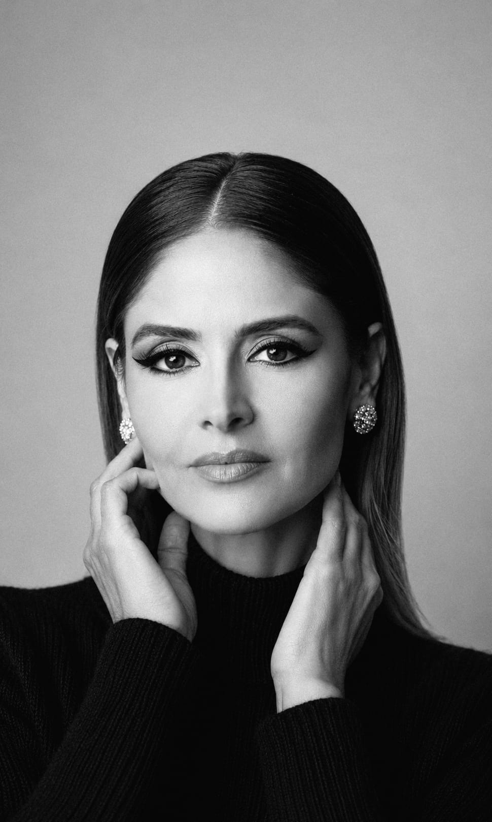 Retrato editorial em preto e branco — mulher em suéter escuro, olhar contemplativo junto à janela.